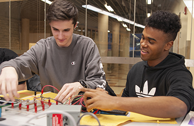 Two students working at a desk in a lab